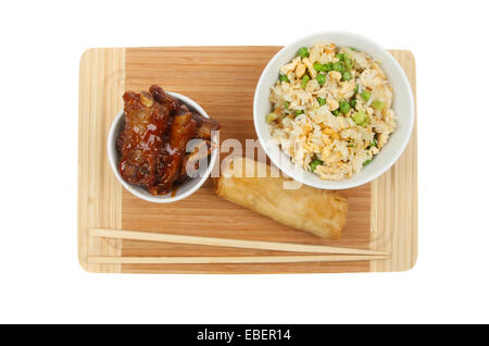 Chinesische Snacks, Spareribs, Pfannkuchen Rollen und Ei gebratenen Reis mit Stäbchen auf einem Bambus-Brett isoliert gegen weiß Stockfoto