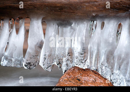 Detailansicht der Eiszapfen hängen vom Protokoll über Wasser und einem einzelnen Felsen. Stockfoto