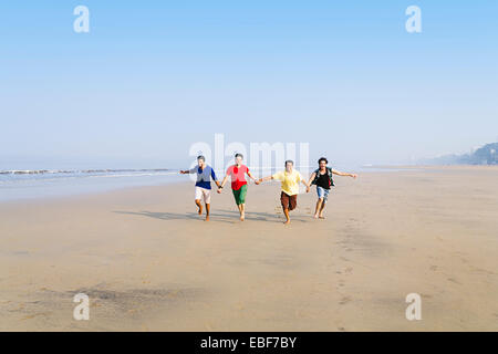 indische Freunde am Strand laufen Stockfoto