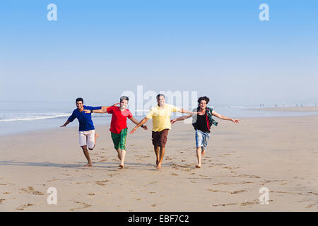 indische Freunde am Strand laufen Stockfoto