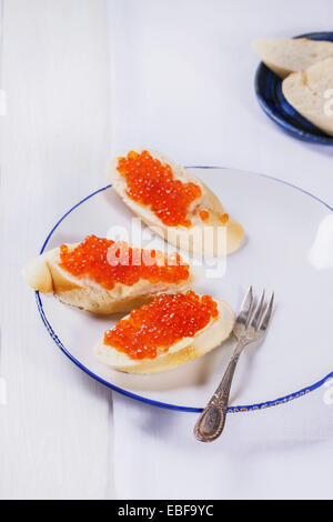 Sandwiches mit rotem Kaviar auf weißen Teller serviert mit Vintage Gabel über weißen Tisch Stockfoto