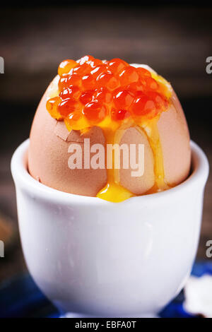 Frühstück mit wachsweiches Ei mit rotem Kaviar in weiß Eierbecher über blaue Keramik Teller serviert. Serien ansehen Stockfoto