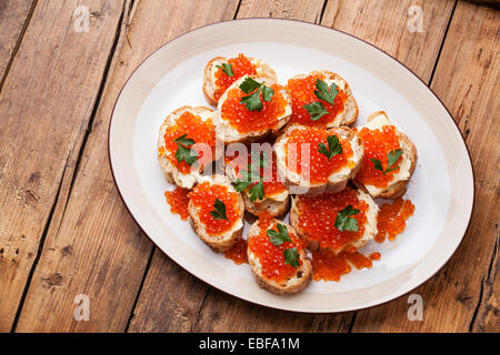 Sandwiches mit Lachs rot Kaviar und Petersilie auf weißen Teller auf hölzernen Hintergrund Stockfoto