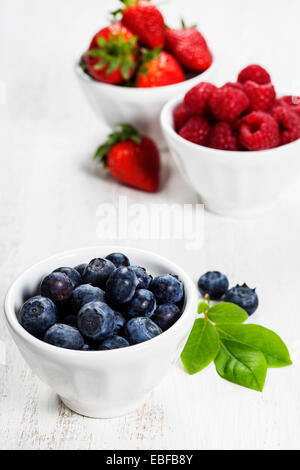 Beeren in Schalen auf hölzernen Hintergrund. Erdbeeren, Himbeeren und Heidelbeeren.  Gesundheit, Ernährung, Gartenbau, Ernte-Konzept Stockfoto