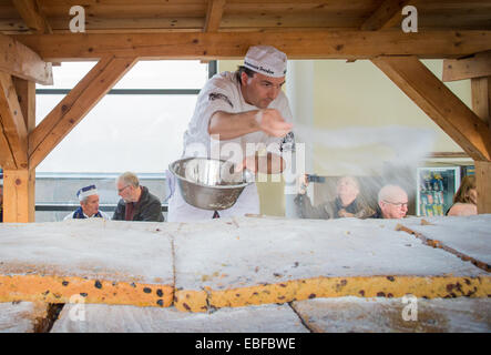 Dresden, Deutschland. 30. November 2014. Ein Dresdner Bäcker deckt der Riesenstollen mit Puderzucker in der neuen Messe in Dresden, Deutschland, 30. November 2014. Die riesige Kuchen besteht aus 40 Stück Stollen. Riesenstollen mit werden für das Stollen-Fest am 6. Dezember 2014 geschnitten. Foto: OLIVER KILLIG/Dpa/Alamy Live News Stockfoto