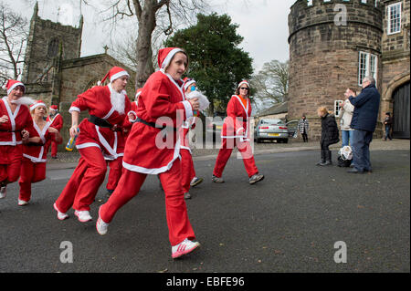 Menschen (Männer, Frauen und Kinder) in rot & weiß Vater Weihnachten Outfits gekleidet sind Wandern, Joggen, Laufen und die Teilnahme an der großen Skipton Santa Fun Run, eine jährliche fundraising Charity Rennen vom Rotary Club - Skipton Stadtzentrum, dem North Yorkshire, England, Großbritannien organisiert. Stockfoto