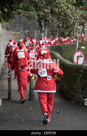 Menschen (Männer, Frauen und Kinder) in rot & weiß Vater Weihnachten Outfits gekleidet sind Wandern, Joggen, Laufen und die Teilnahme an der großen Skipton Santa Fun Run, eine jährliche fundraising Charity Rennen vom Rotary Club - Skipton Stadtzentrum, dem North Yorkshire, England, Großbritannien organisiert. Stockfoto