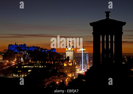 Edinburgh, Schottland. 30. November 2014. Edinburgh Castle und die Stadt bei Sonnenuntergang das Schloss leuchtet mit blauer Beleuchtung während der St. Andrews Day Feierlichkeiten, zeigt auch das Riesenrad und die Star Flyer von Calton Hill gesehen fährt neben dem Scott Monument in Princes Street Gardens East liegt. Stockfoto