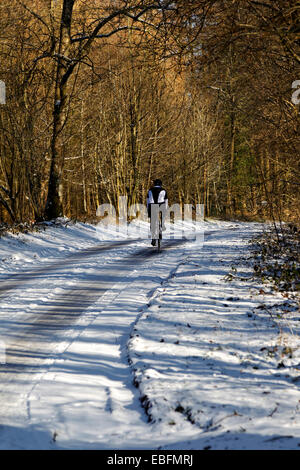 Eine männliche Radsportler, entlang einer Straße Schnee bedeckte Landschaft im Winter. Stockfoto