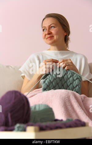 glückliche junge Frau stricken auf sofa Stockfoto