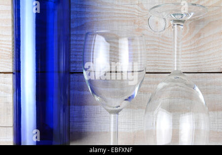 Hohen Winkel Schuss eine blaue Flasche Wein und zwei Gläser Wein auf einem rustikalen weißer Holztisch. Querformat. Stockfoto