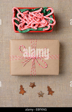 Hohen Winkel Schuss aus einer Schüssel voller Mini candy Canes, ein normales Papier eingewickelt Weihnachtsgeschenk und Baum und Stern antike Dekoration Stockfoto