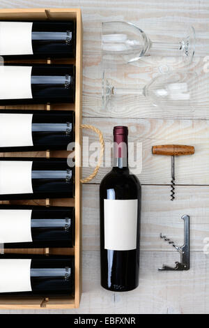 Hohen Winkel Schuss des Schrankes roten Wein Flaschen neben einer einzigen Flasche zwei Weingläser und Korkenzieher auf einer rustikalen weiße Holz-Registerkarte Stockfoto