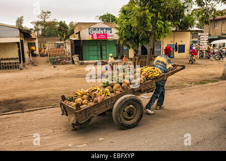 Afrikanischer Mann ziehen einen Karren voller Früchte in einer Einkaufsstraße von Arusha Stockfoto