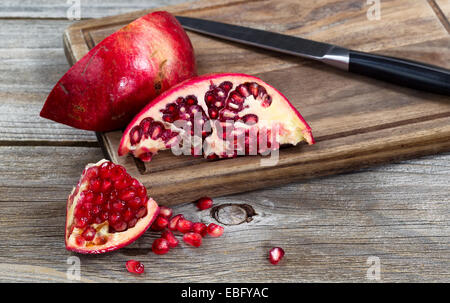 Nahaufnahme von saftige Reife Granatäpfel mit Messer auf Vintage Holz server Stockfoto