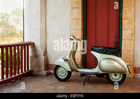 1958 grün-Vespa-Roller vor einer roten rustikale Tür Stockfoto