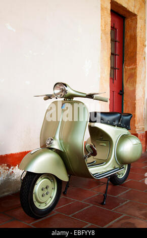 Jahrgang 1958-grüne Vespa-Roller vor einem rustikalen Gebäude Stockfoto