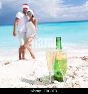 Glückliches Paar feiert Weihnachten mit Sekt am Strand Stockfoto