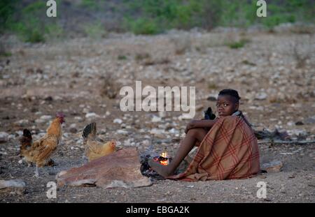 Junge Schäferin aus der Himba Leute sitzen am Lagerfeuer, Ombombo, Kaokoland, Kunene, Namibia Stockfoto