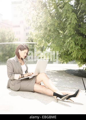 Frau trägt einen Business-Anzug sitzt mit einem Laptop im Park, Innsbruck, Tirol, Österreich Stockfoto