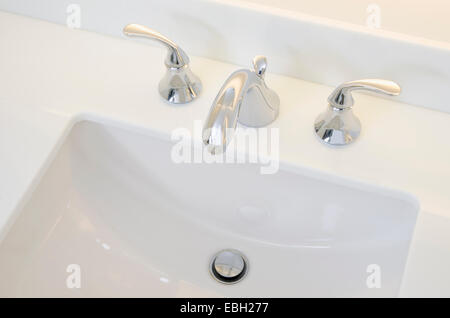 Waschbecken im Badezimmer und Zähler: Nahaufnahme eines Badezimmer Waschbecken, Chromhahn und weiße Theke. Stockfoto