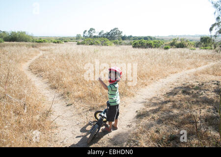 Junge auf Pfad im Feld mit Fahrrad Stockfoto