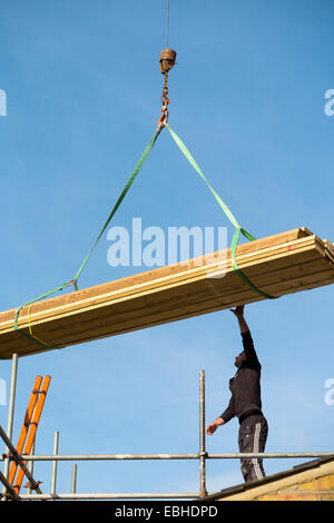 Holz geliefert per Kran eine Arbeiter-Builder auf Gerüsten & viktorianischen Reihenhaus Hausdach. Sieht aus wie der Buchstabe A. UK. Stockfoto