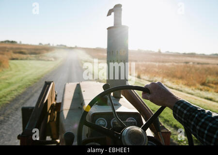 Schulter-Blick über senior männlichen Bauer Traktor fahren auf der Landstraße, Plattsburg, Missouri, USA Stockfoto