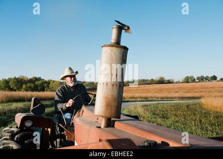 Ältere männliche Bauer Traktor fahren auf der Landstraße, Plattsburg, Missouri, USA Stockfoto