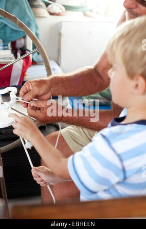 Nahaufnahme von Großvater und Enkel binden von Knoten auf Segelboot Stockfoto
