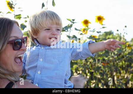 Mitte erwachsenen Frau und Kleinkind Sohn zeigt im Sonnenblumenfeld Stockfoto