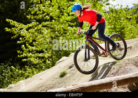 Junge weibliche bmx-Biker Beschleunigung nach unten Felsen im Wald Stockfoto