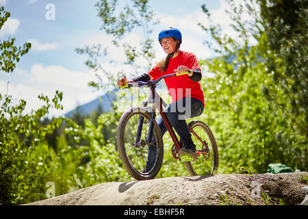 Junge weibliche bmx-Biker am Rand der Felsen im Wald Stockfoto