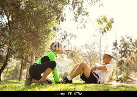 Reifen laufen paar tun Sit ups im Park Stockfoto