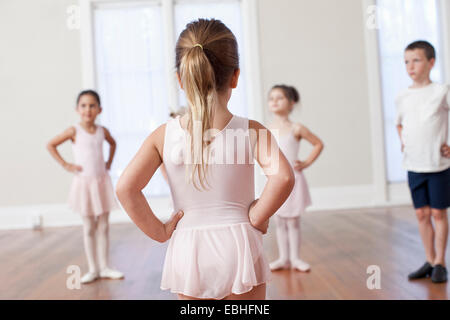 Vier Kinder üben Ballett mit Händen auf den Hüften in die Ballettschule Stockfoto