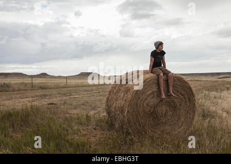 Teenager sitzen auf Heuhaufen im Feld, South Dakota, USA Stockfoto