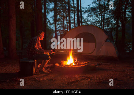 Mann, Kochen am Lagerfeuer im Wald bei Nacht, Arkansas, USA Stockfoto