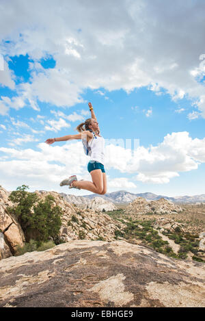 Frau springen vor Freude auf Berg, Joshua Tree Nationalpark, Kalifornien, USA Stockfoto