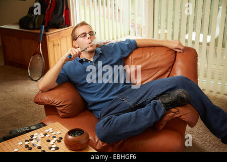 Junger Mann Rauchen auf sofa Stockfoto