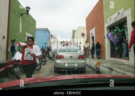 Verkehr und überfüllten Bürgersteig mit Mexikanischen und Maya Menschen Einkaufen in der historischen Altstadt von Campeche, Mexiko gesehen durch Auto Wind. Stockfoto