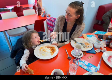 Mutter und Tochter / Kind / Kinder haben Familienfrühstück Bohnen Ei Toast. Kleinen Koch am Straßenrand Schnellrestaurant / Imbiss UK Stockfoto