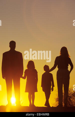 Familie in der Silhouette bei Sonnenuntergang Stockfoto