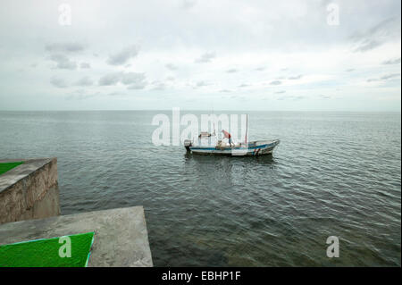 Ruhiges Bild eines einsamen Fischers auf einem Panga-Boot mit einem Push-Pole auf der Bucht von Campeche unter niedrigen Wolken im Morgenlicht, Mexiko Stockfoto