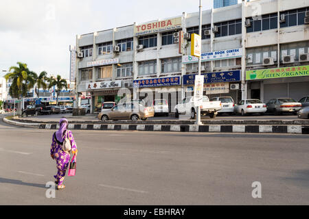 Frau Kreuzung Straße vor den Geschäften, Miri, Malaysia Stockfoto