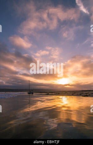 Ein atemberaubender Sonnenuntergang über einem Segelboot spiegelt sich in der Brandung des Coronado Island in der Nähe von San Diego, Kalifornien Stockfoto