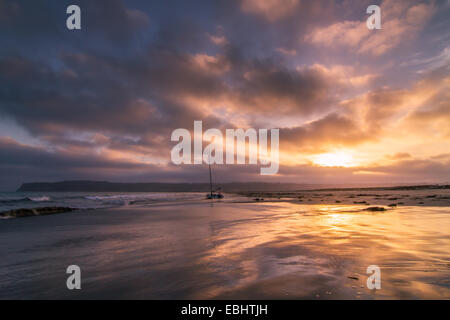 Ein atemberaubender Sonnenuntergang über einem Segelboot spiegelt sich in der Brandung des Coronado Island in der Nähe von San Diego, Kalifornien Stockfoto