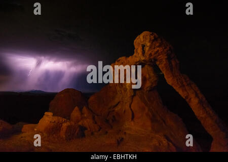 Lila Bolzen von Blitzeinschlägen hinter Elefanten Felsbogen auf Nevadas Valley of Fire State Park Stockfoto