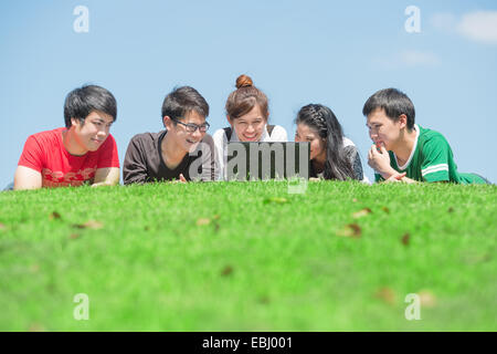 Gruppe von Studenten im Freien auf dem Rasen liegen und auf der Suche nach computer Stockfoto