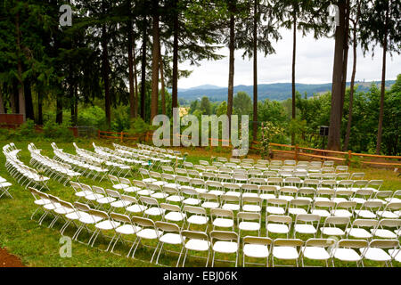 Hochzeit Zeremonie an einem Veranstaltungsort mit Gras, Bäume, und weißen Stühlen. Stockfoto