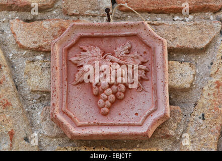 Dekorative Fliesen mit Weinrebe fest auf einen Stein Wand außerhalb eine Wein-Bar / shop in Italien, Europa. Stockfoto